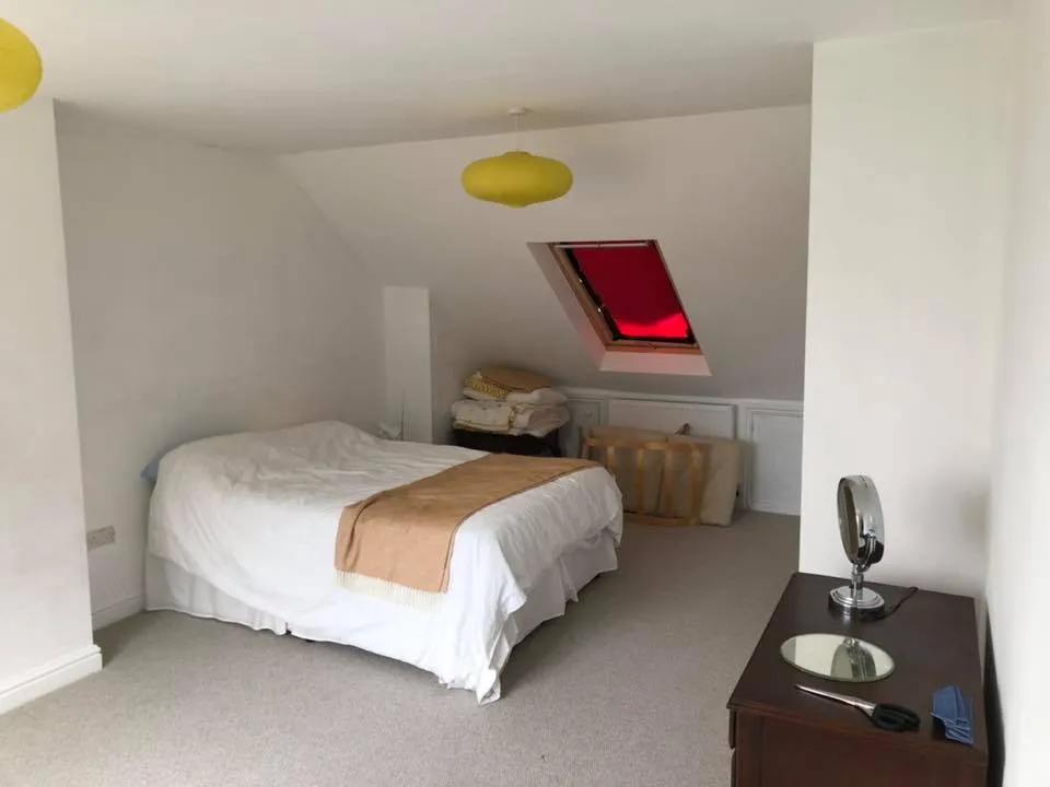a bedroom with a bed, dresser and a window