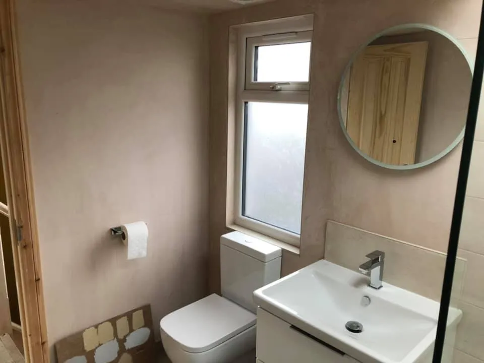 a bathroom with a toilet, sink and mirror